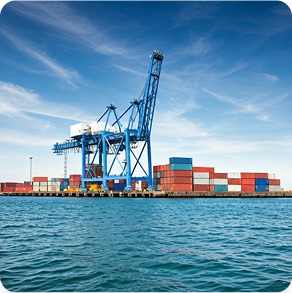 Blue port cranes and stacked containers by the sea